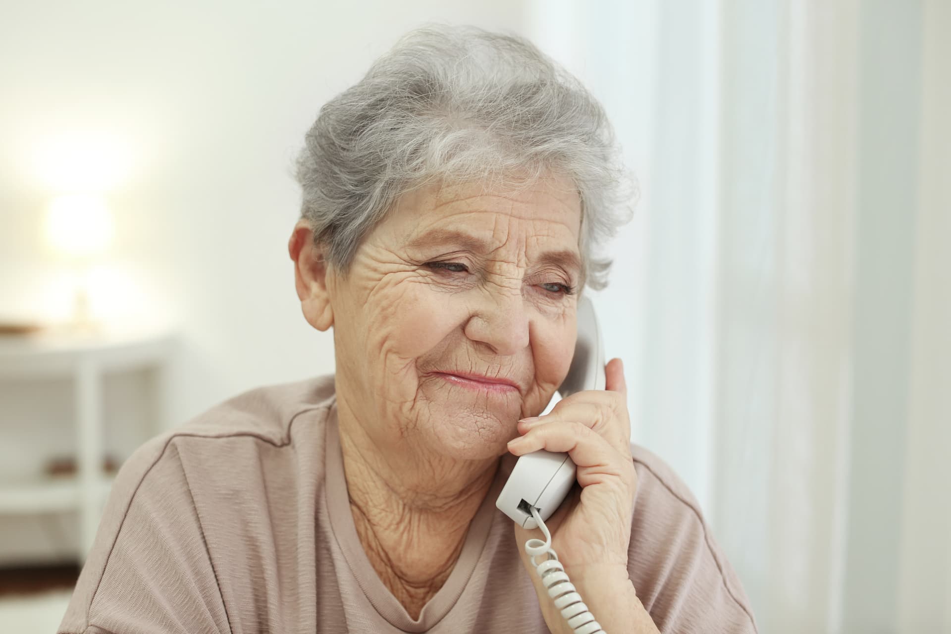 A senior woman smiling while talking on her home phone